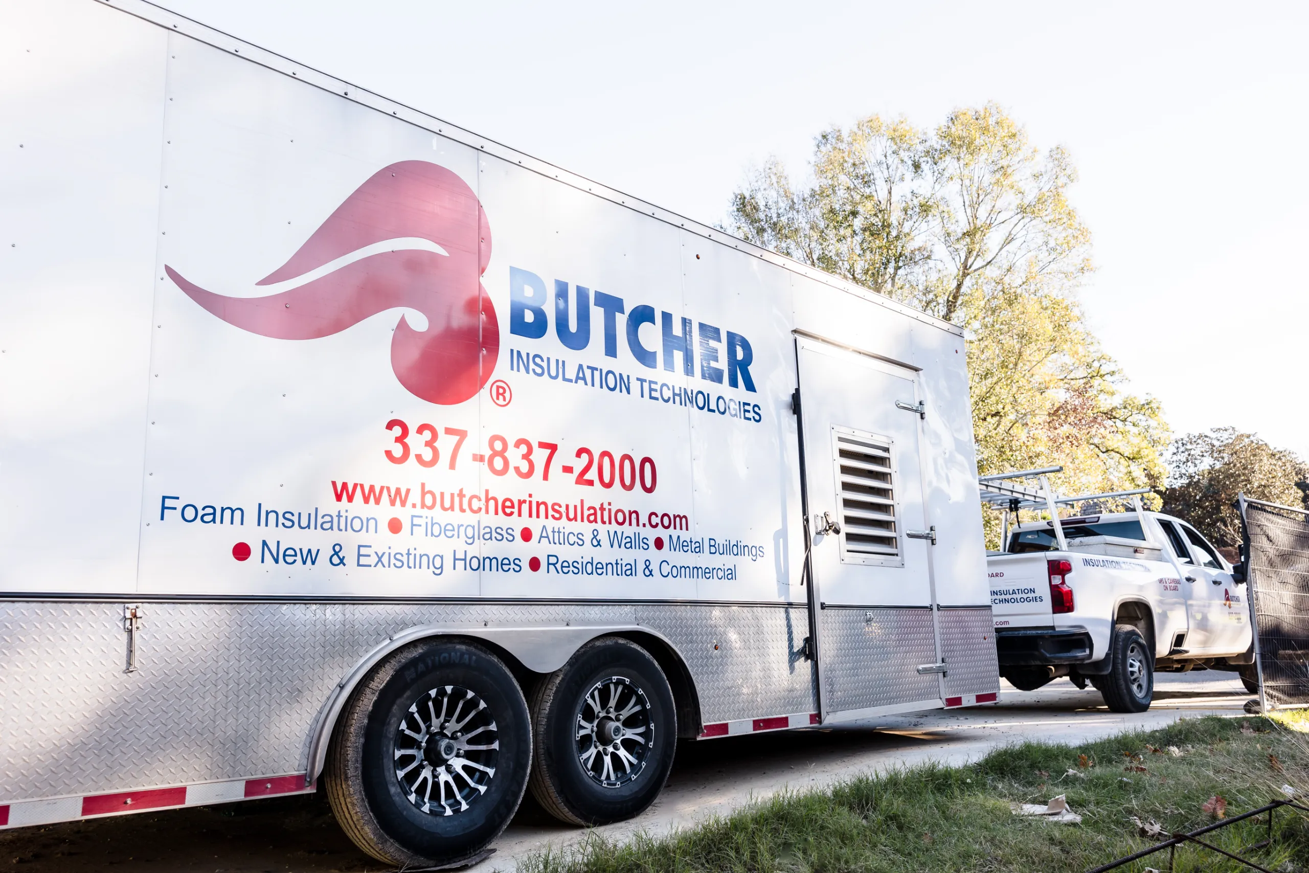 Butcher Insulation Technologies trailer and pickup with large logo, phone number and equipment parked at job site