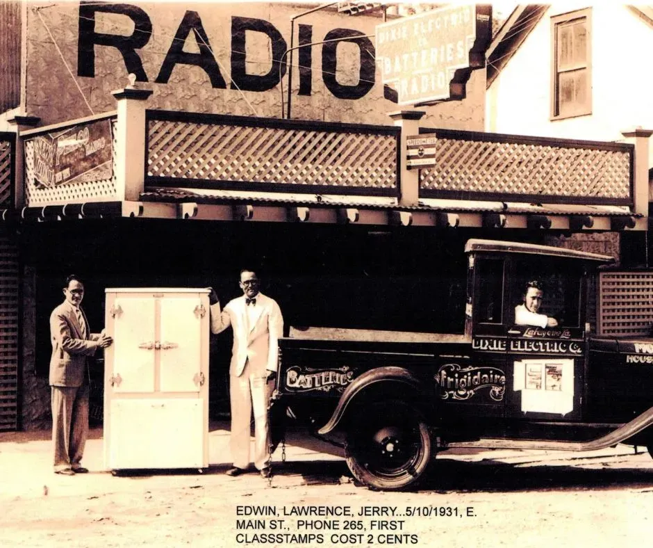 Vintage 1931 radio shop storefront with Frigidaire delivery truck and two men posing beside an early refrigerator
